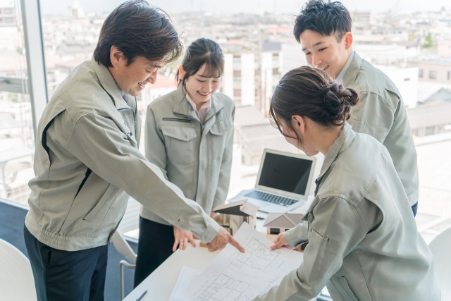 資料を見てミーティングする作業着を着た社員たち
