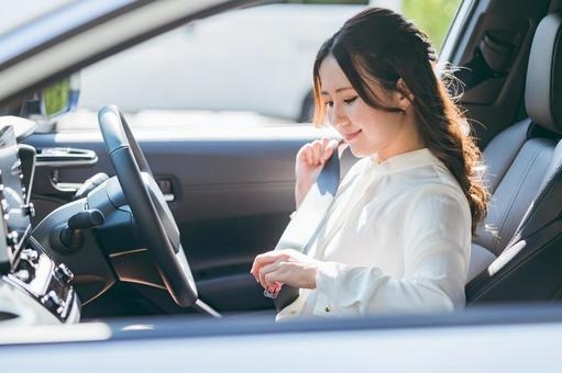 運転席でベルトを装着する女性